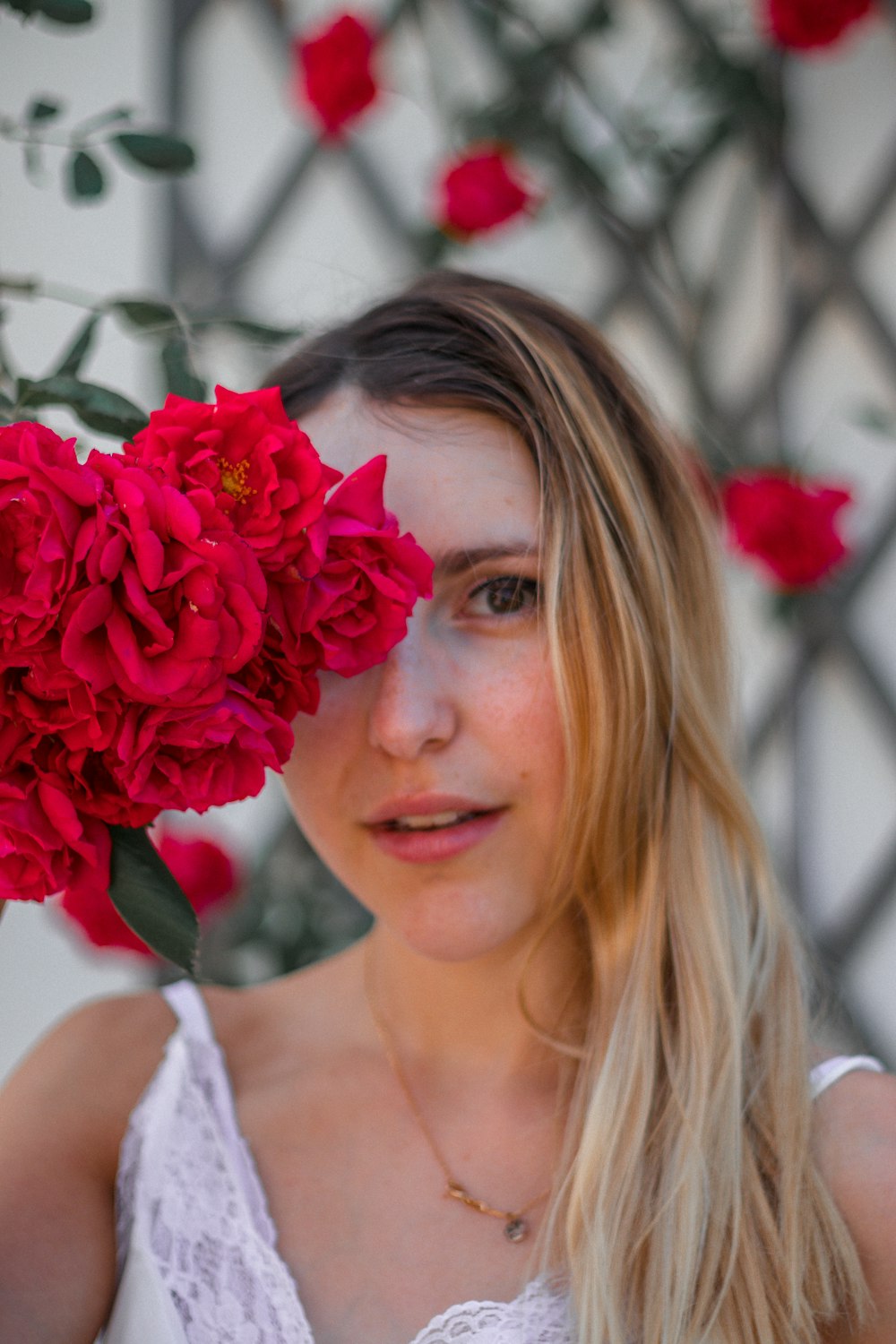 Femme en débardeur blanc tenant un bouquet de roses rouges