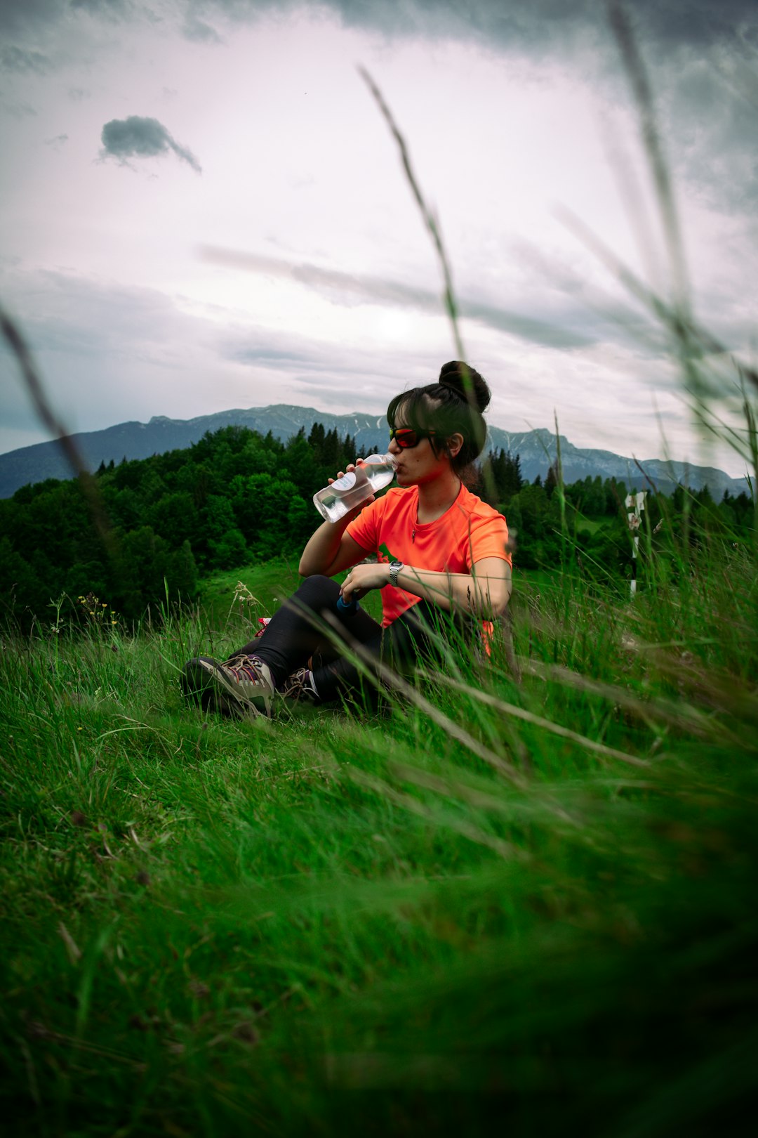 man in orange shirt and black pants sitting on green grass field