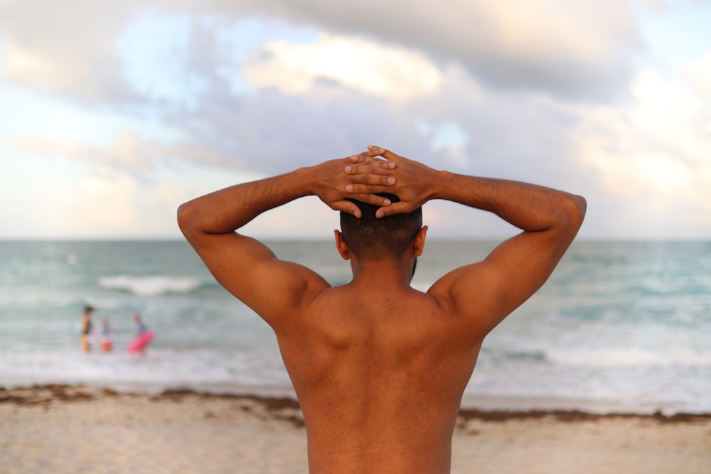 topless man standing on beach during daytime