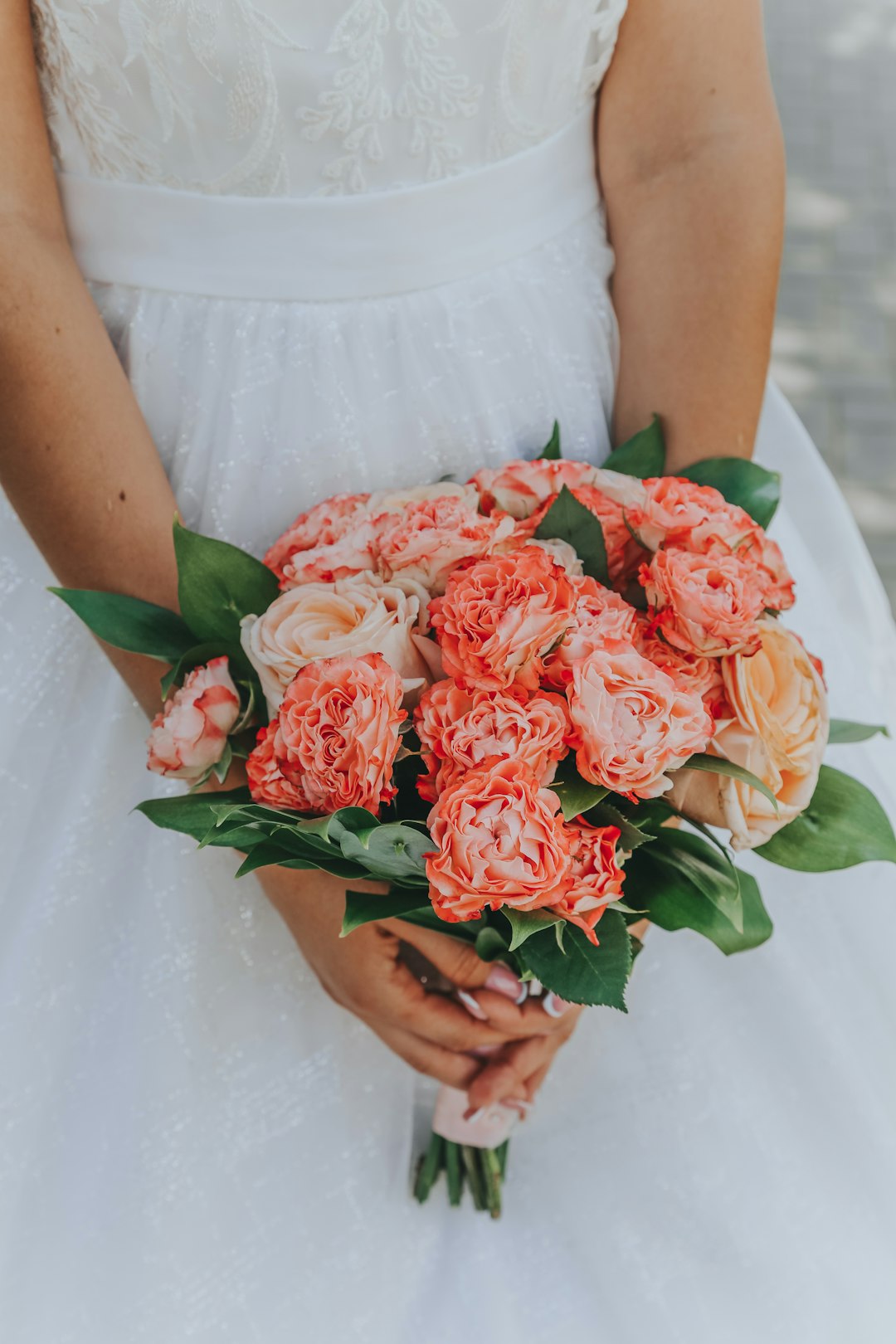 woman in white dress holding red rose bouquet