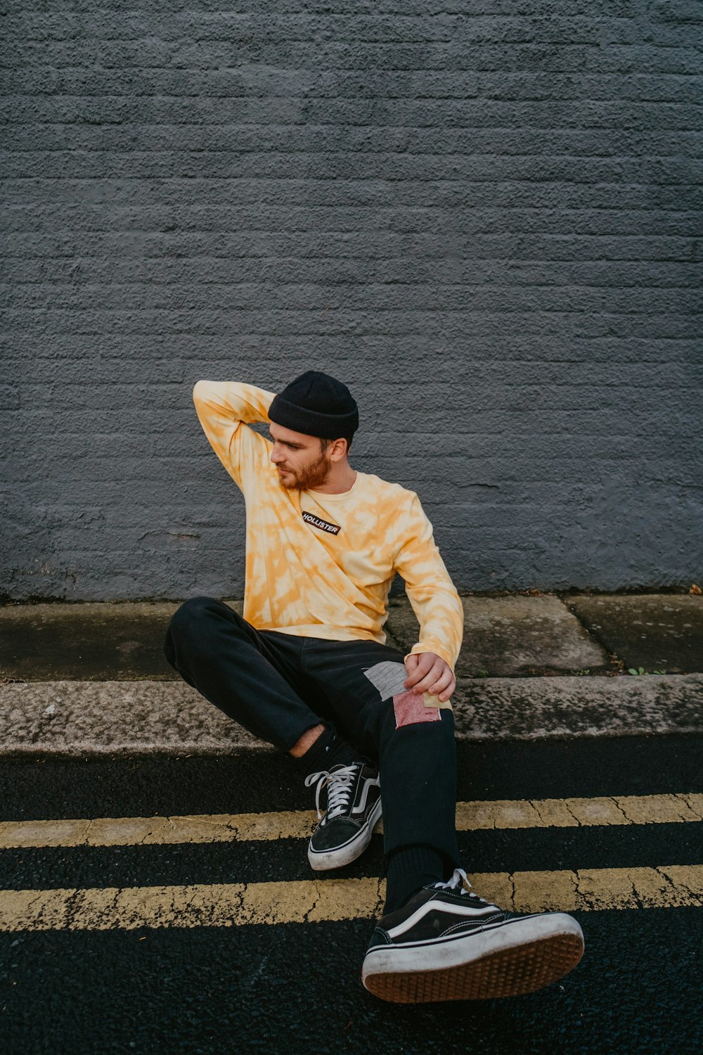 man in brown jacket and black pants sitting on concrete stairs