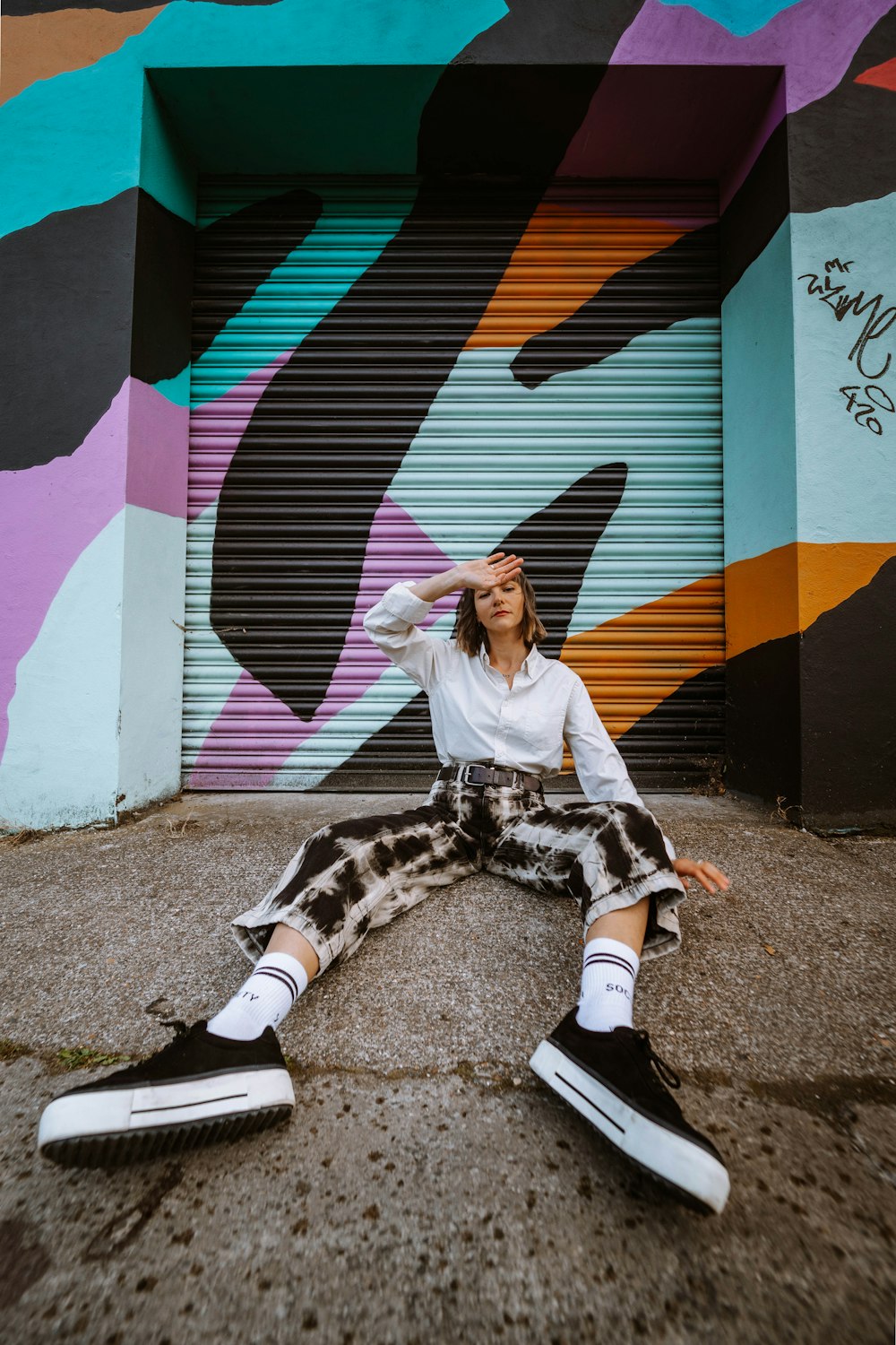 woman in white long sleeve shirt and black pants sitting on ground