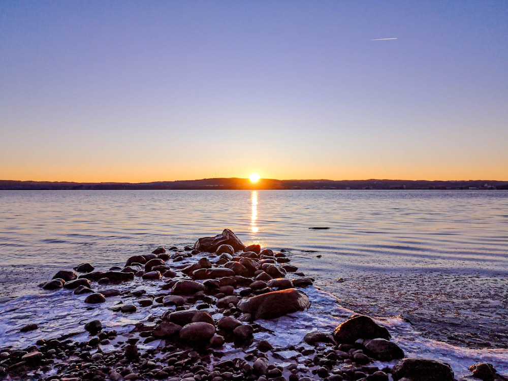 gray rocks on sea shore during sunset