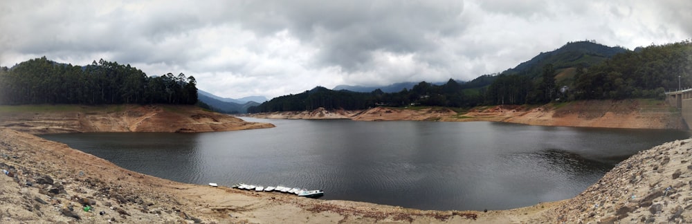 body of water near mountain under cloudy sky during daytime