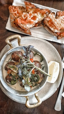 A vibrant plate of spicy raw meatballs garnished with fresh herbs.