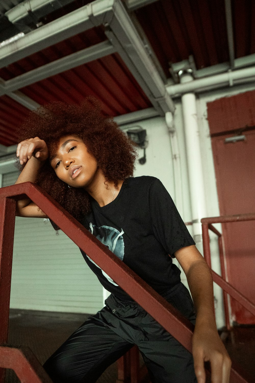 woman in black crew neck t-shirt leaning on red metal railings