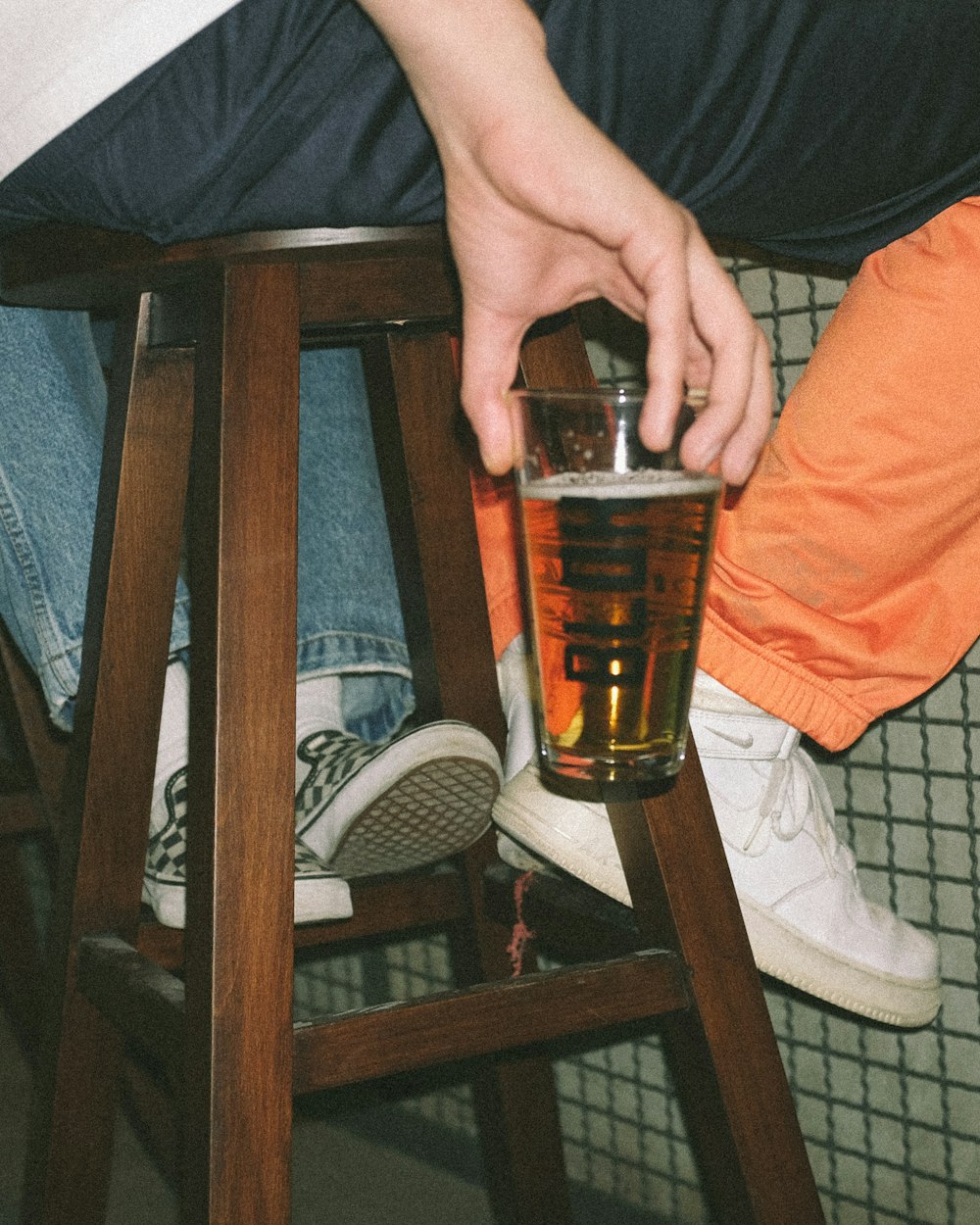 person holding clear drinking glass with brown liquid