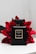A sleek black perfume bottle labeled Coco Noir Chanel Paris is positioned against a backdrop of vibrant red flowers. The bottle's simplistic design and gold accents exude luxury and elegance. The contrast between the dark bottle and the bright flowers creates a striking visual appeal.