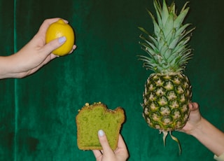 person holding pineapple fruit and pineapple fruit