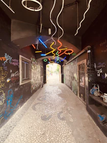 A shadowed alley with vibrant street art illuminated by subtle neon lighting.