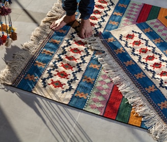 person in blue denim jeans standing on white blue and red area rug