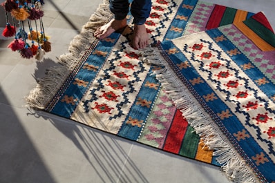 person in blue denim jeans standing on white blue and red area rug