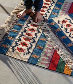 person in blue denim jeans standing on white blue and red area rug