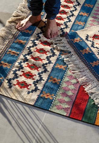 person in blue denim jeans standing on white blue and red area rug