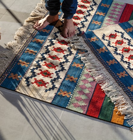 person in blue denim jeans standing on white blue and red area rug