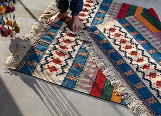 person in blue denim jeans standing on white blue and red area rug