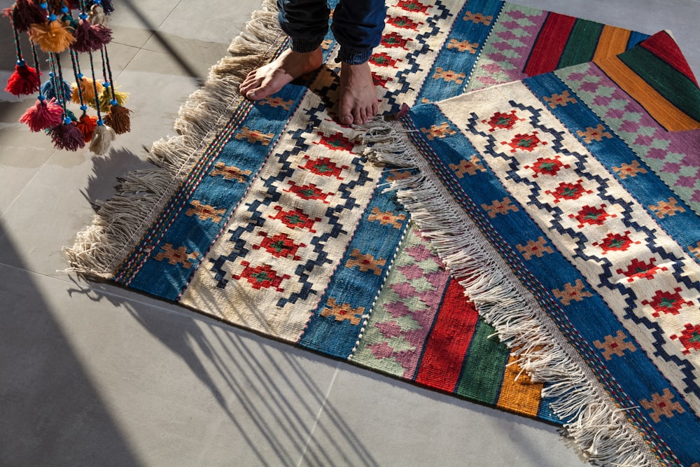 person in blue denim jeans standing on white blue and red area rug