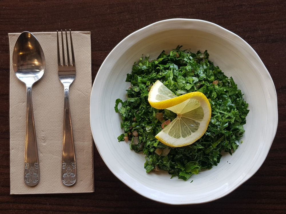 sliced lemon on white ceramic bowl beside stainless steel fork