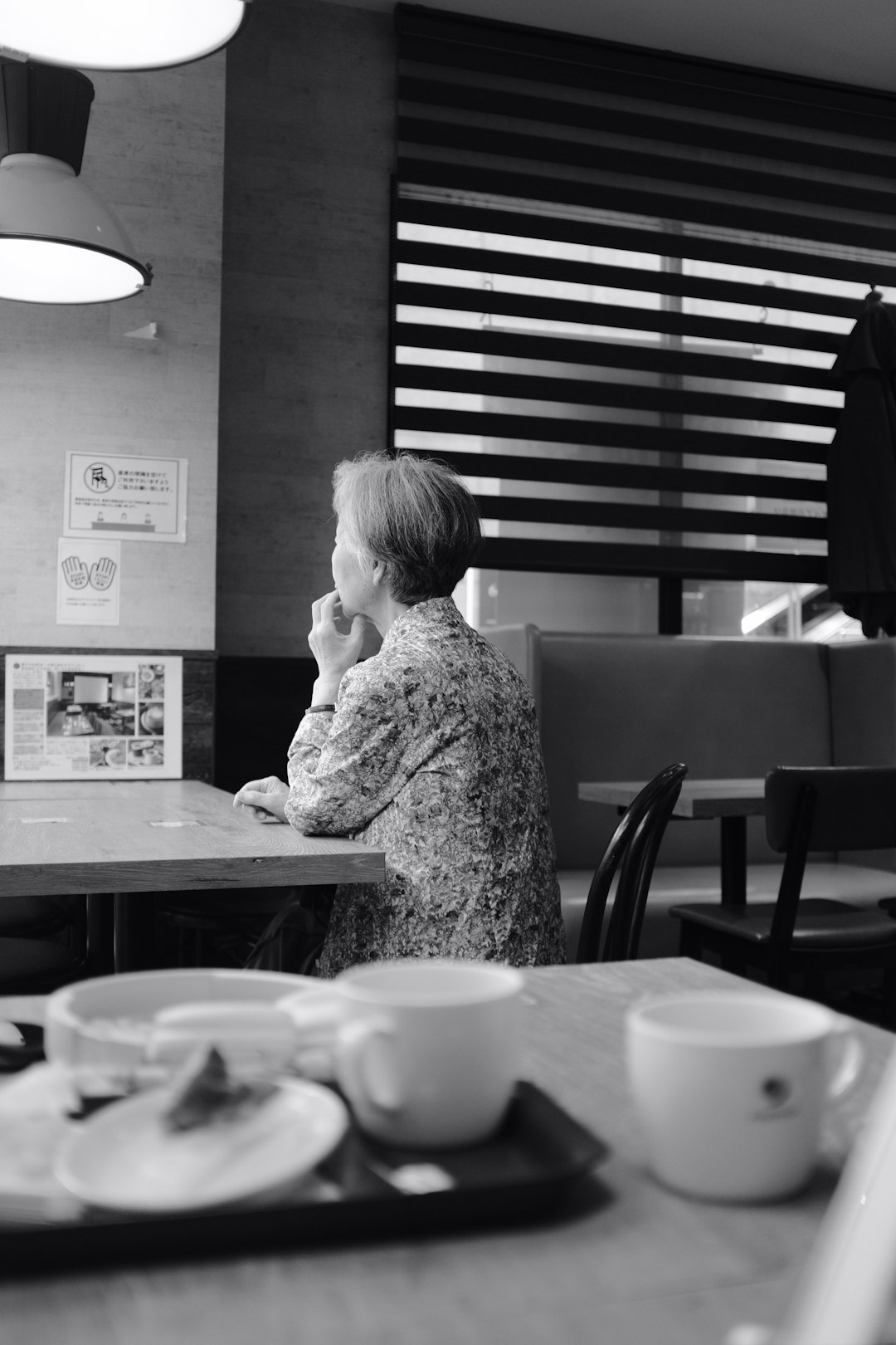 grayscale photo of woman sitting on chair in front of table