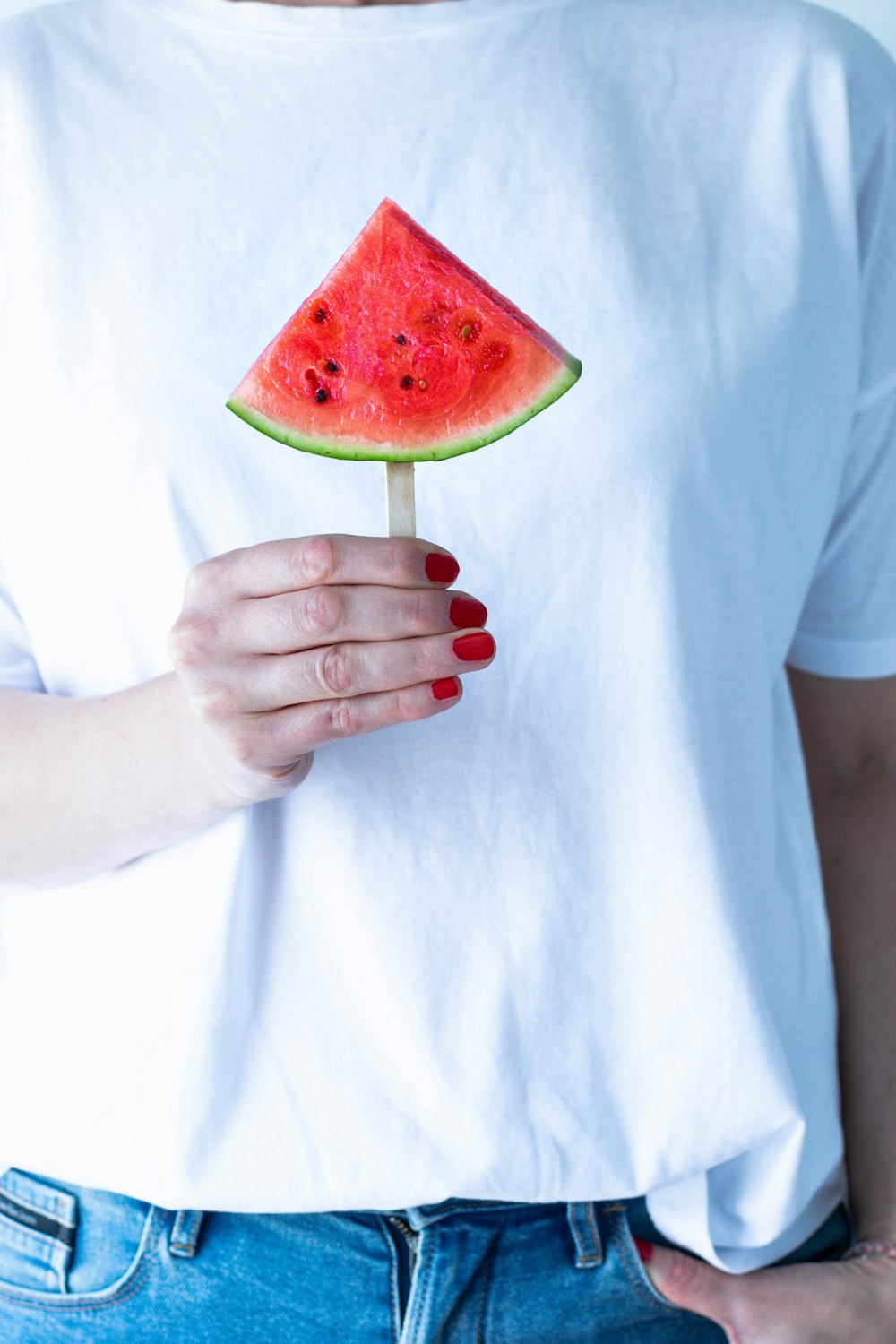 person in white crew neck t-shirt holding watermelon
