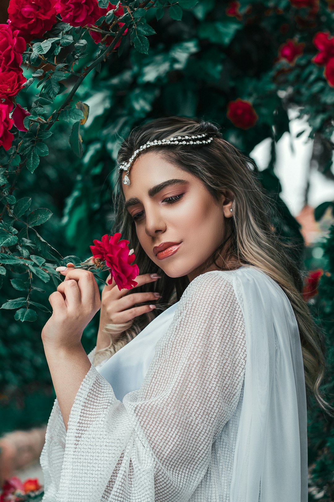 woman in white long sleeve shirt holding red flower