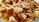 Close-up of crispy fried pork rinds with a golden brown color, displaying a crunchy texture. The pieces are irregularly shaped and piled together, highlighting the savory crust.
