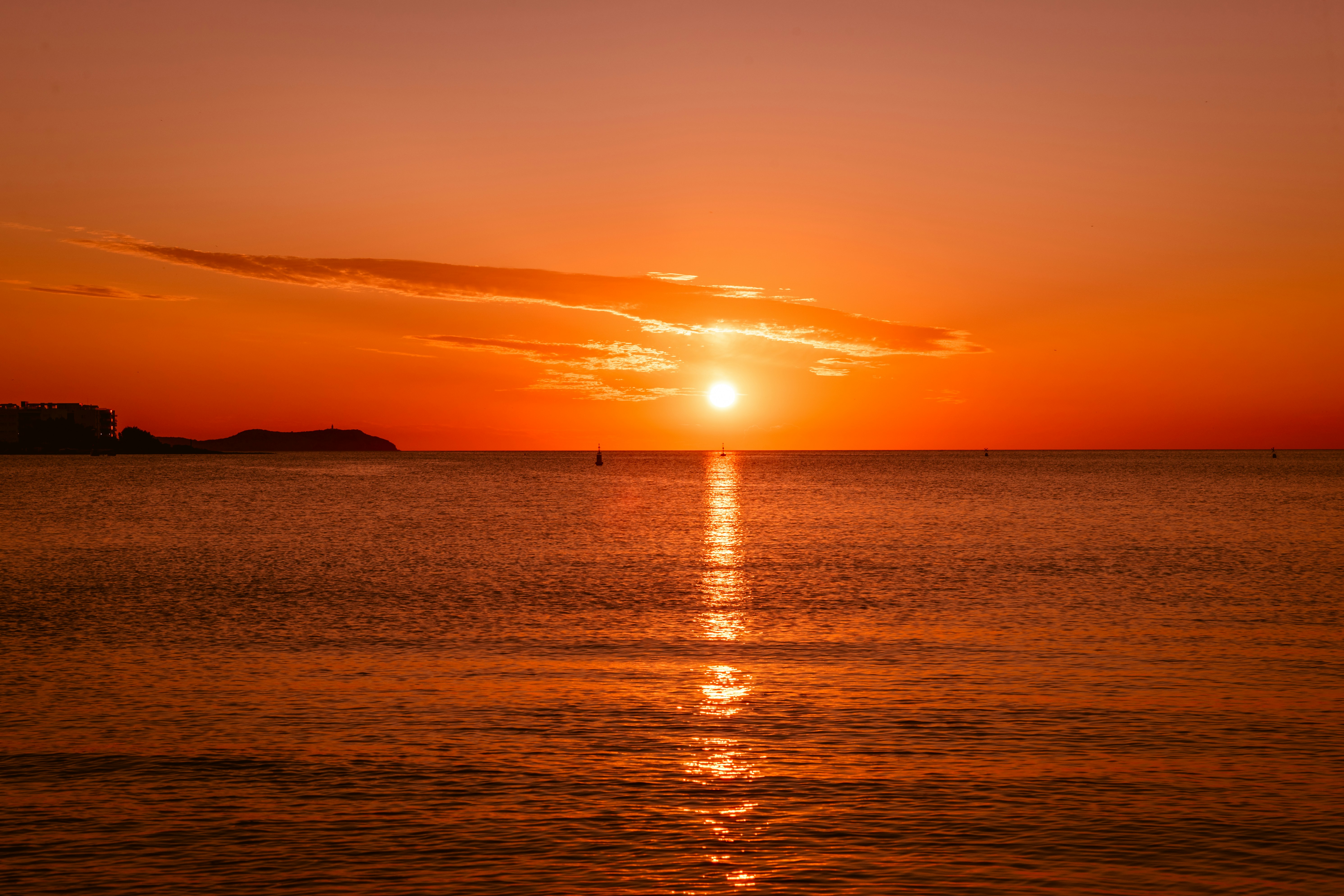 silhouette of person standing on beach during sunset, Golden hour sunset casting an orange glow on clouds and sea.