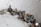 A collection of metallic bolts and screws scattered on a slightly dusty surface. The items vary in size and feature a mix of rust and shine, indicating some are older and worn while others are newer.