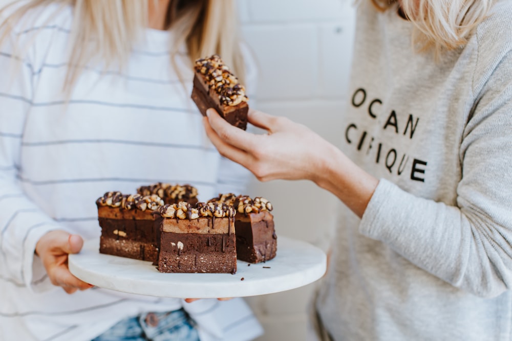 woman holding chocolate cake on white ceramic plate