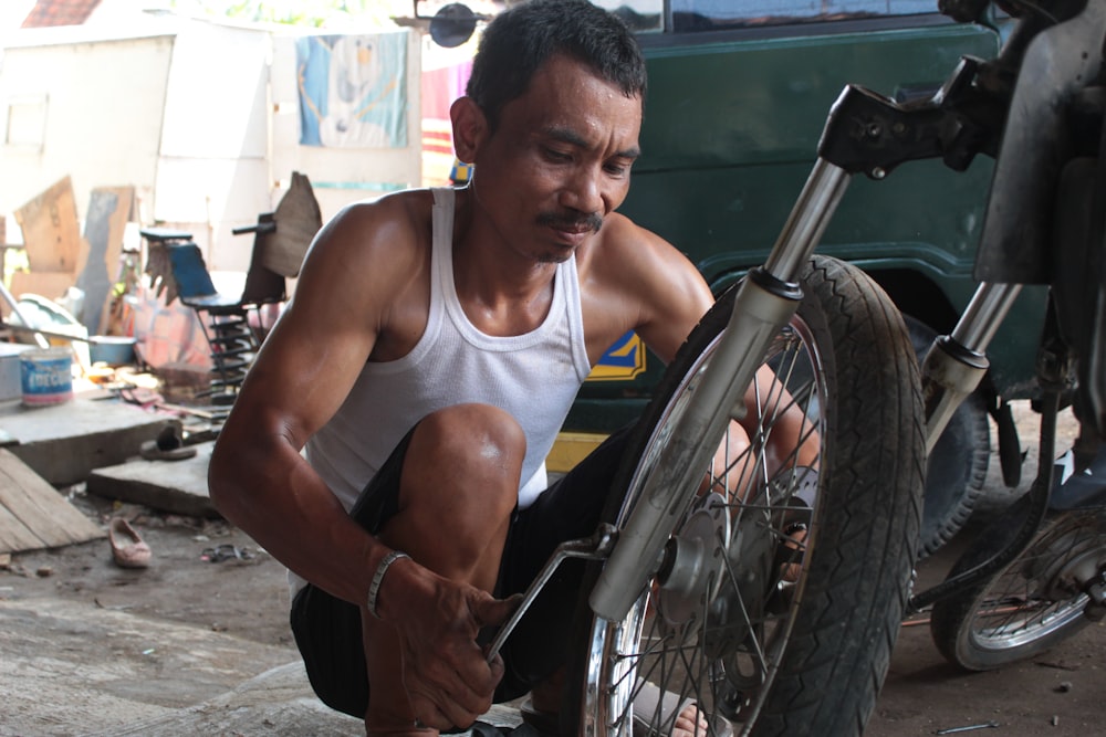 man in white tank top sitting on black wheelchair