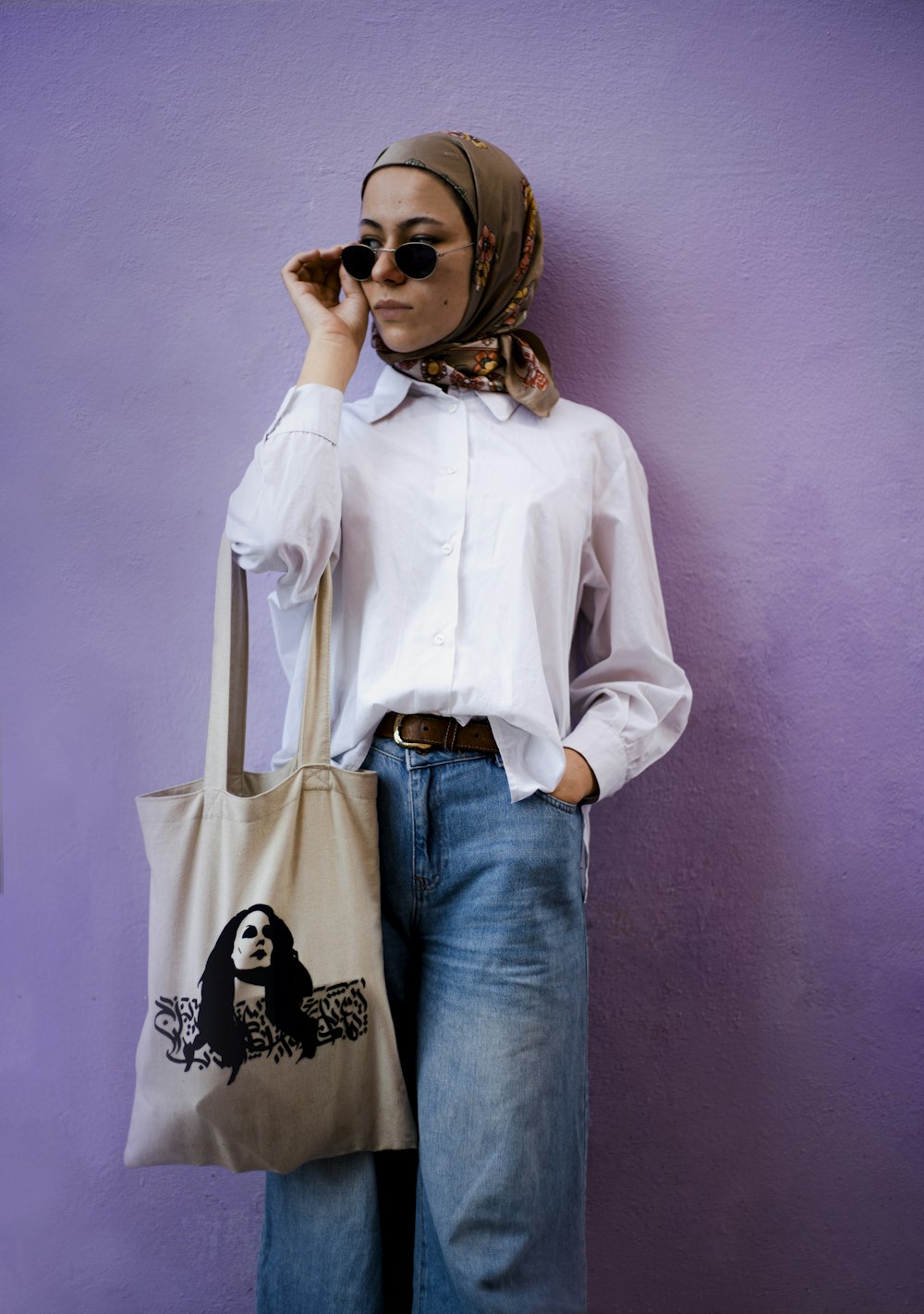 a woman wearing a headscarf and holding a tote bag