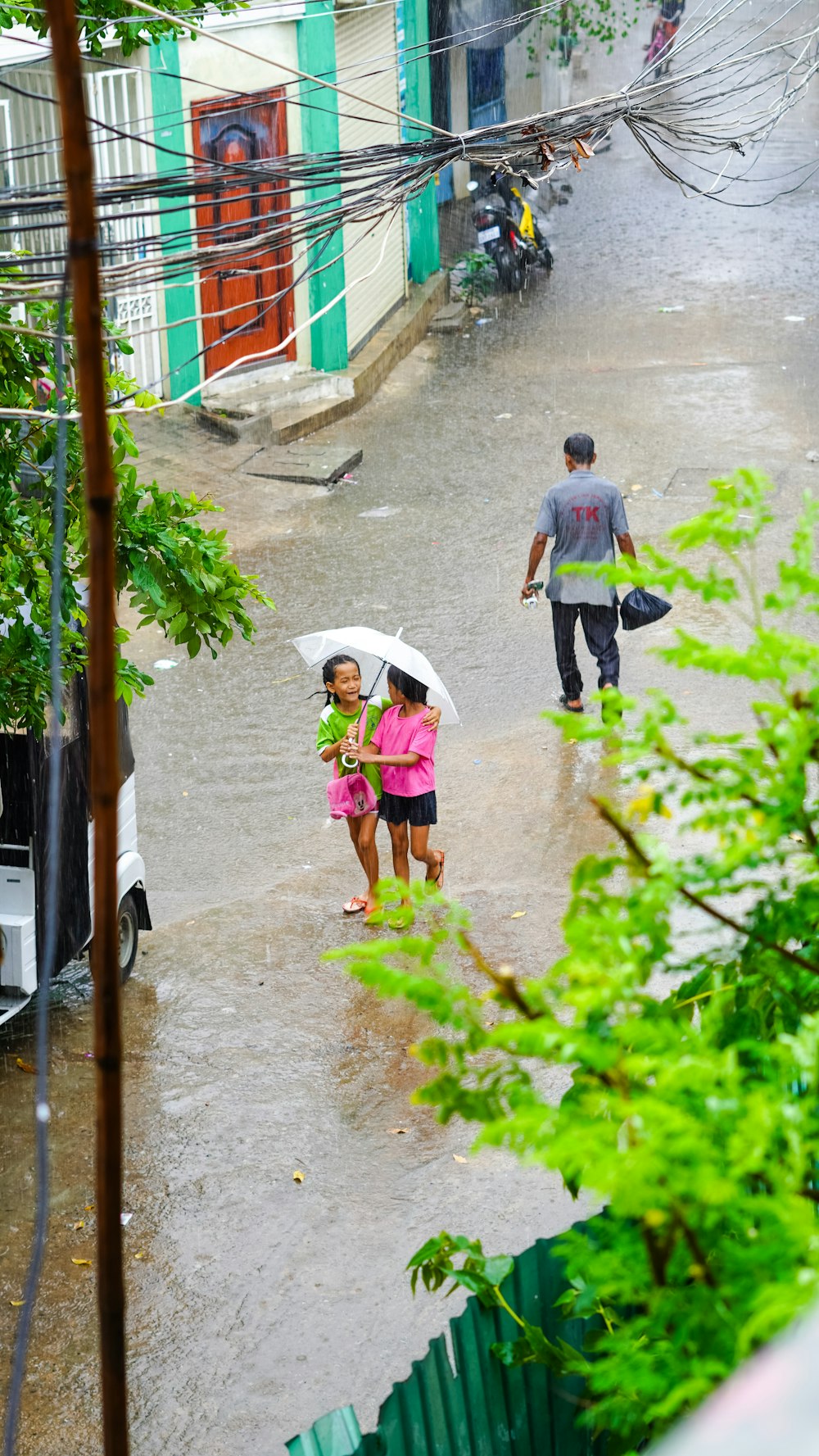 2 niños caminando en la acera sosteniendo un paraguas durante el día