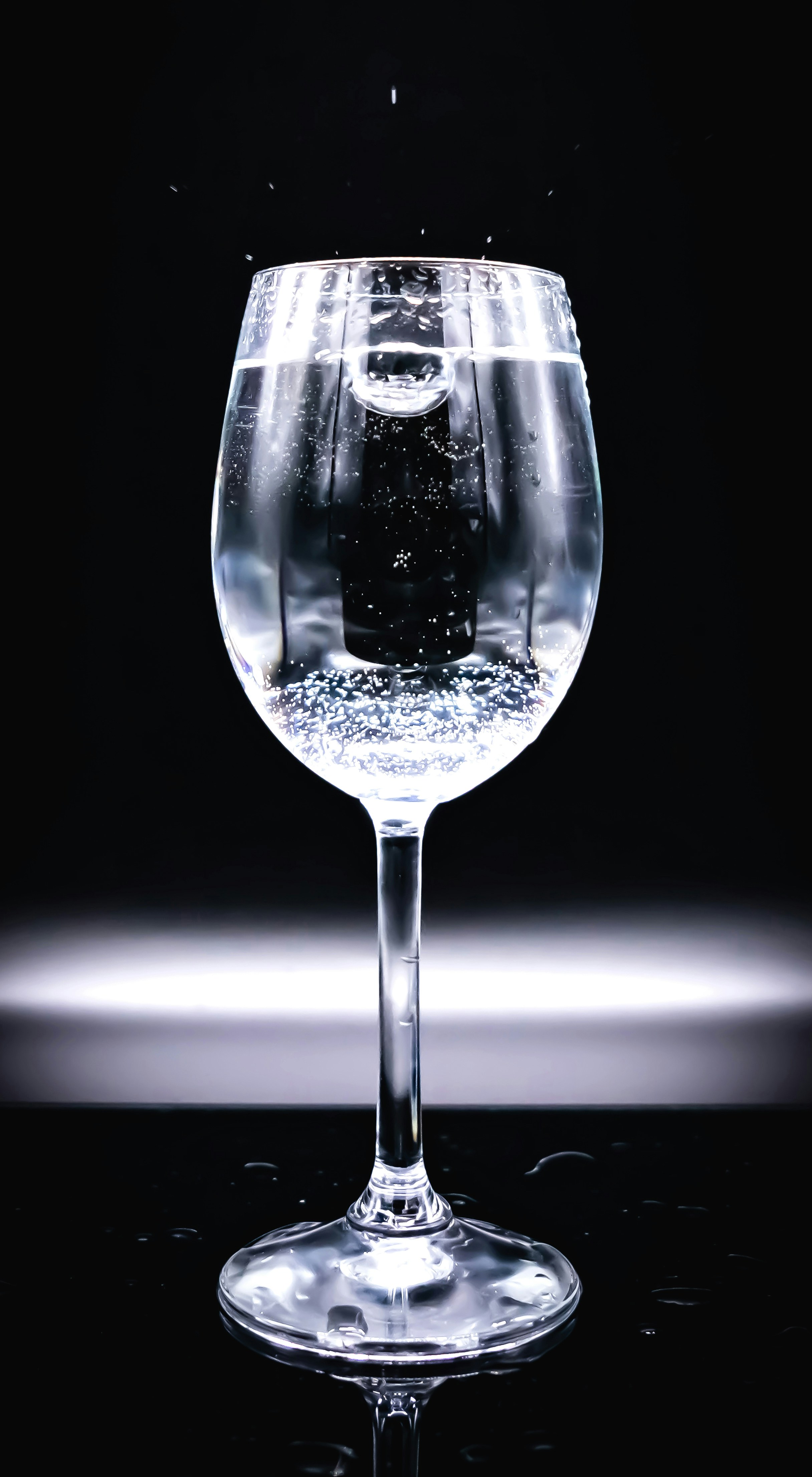 Clear sparkling water with bubbles in glass with ice