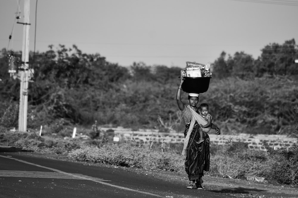 grayscale photo of man in jacket and backpack standing on road