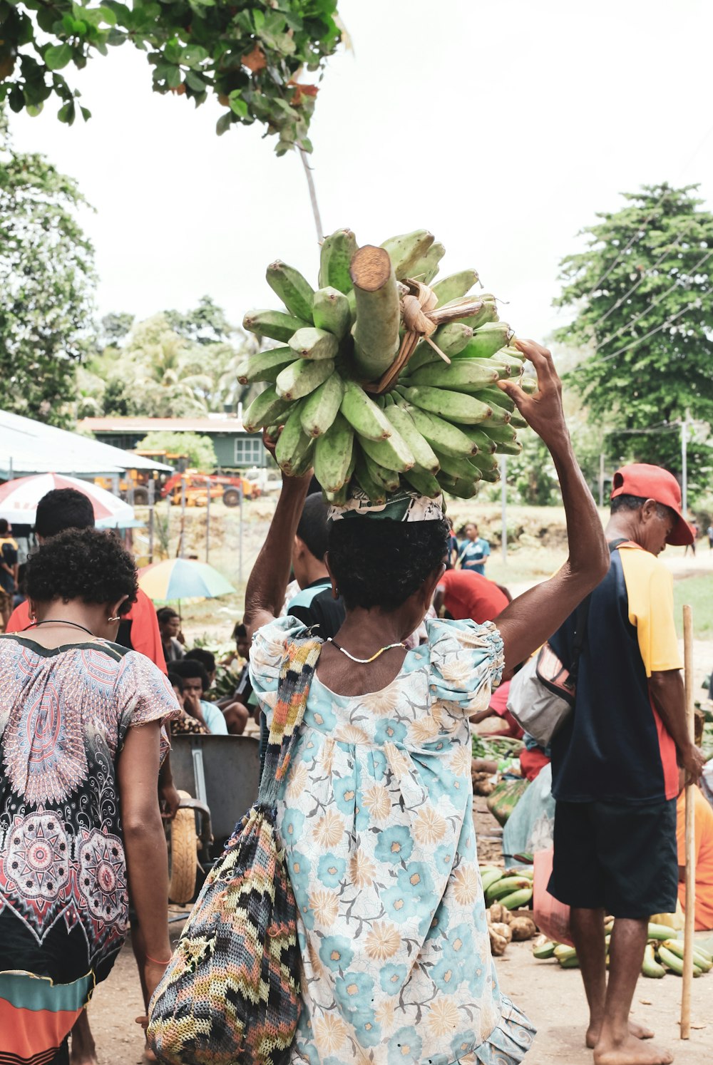 Mujer en vestido floral blanco y azul sosteniendo fruta verde durante el día