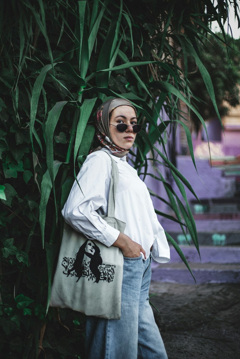 mujer con hiyab blanco de pie junto a plantas verdes