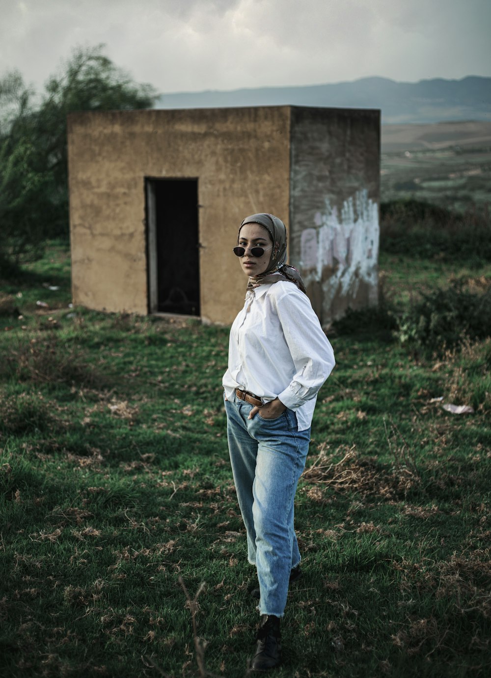 Una mujer parada en un campo al lado de un edificio