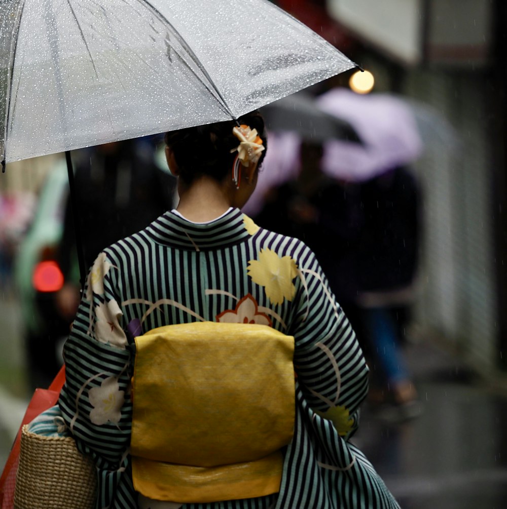 mulher no vestido preto e branco da listra que segura o guarda-chuva