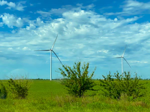 wind turbines on green grass field under blue and white cloudy sky during daytime