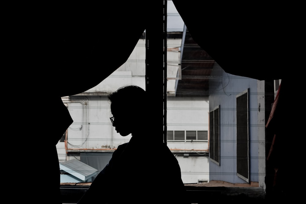 silhouette of person standing near window during daytime
