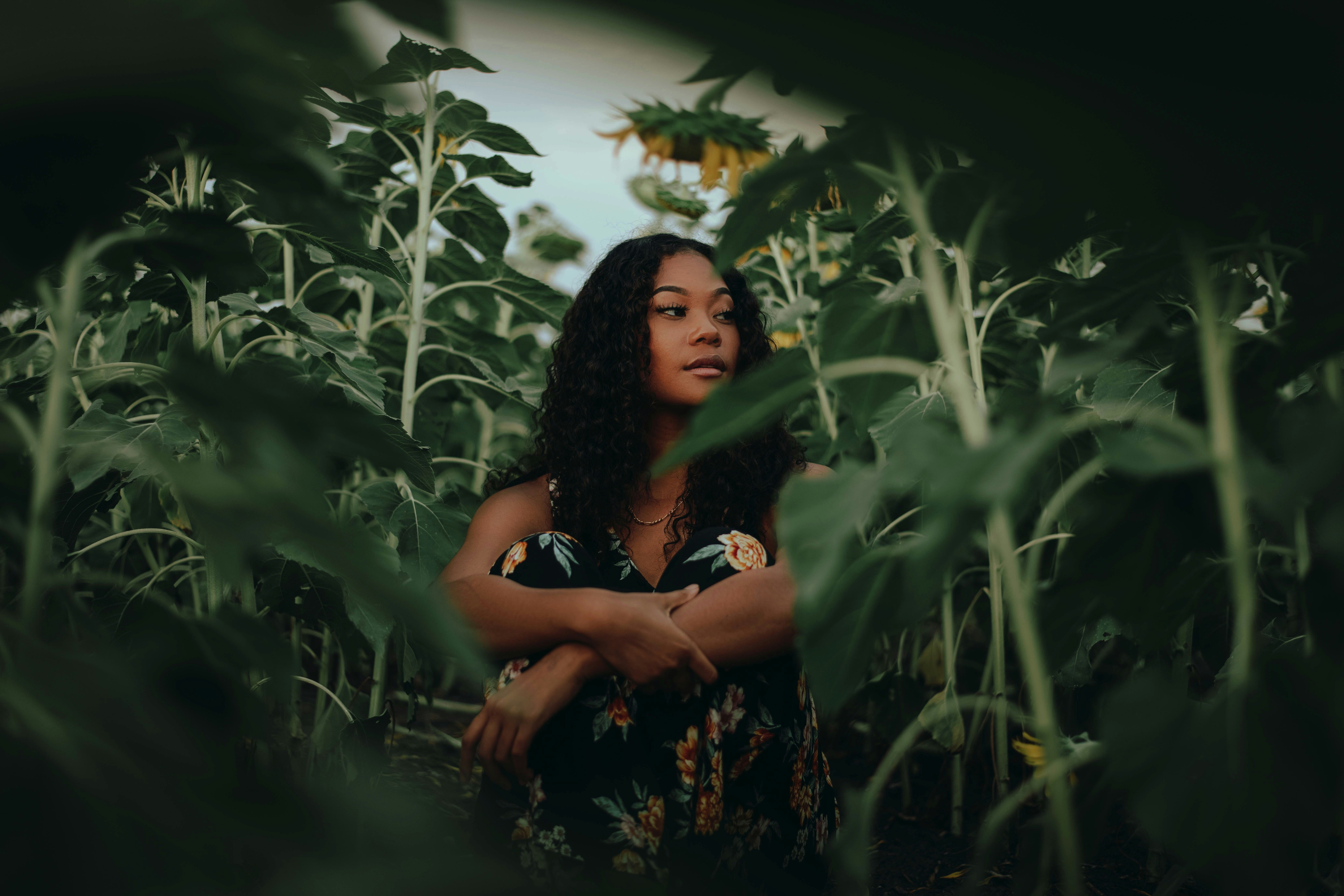 woman in black and brown floral dress standing in the middle of green plants