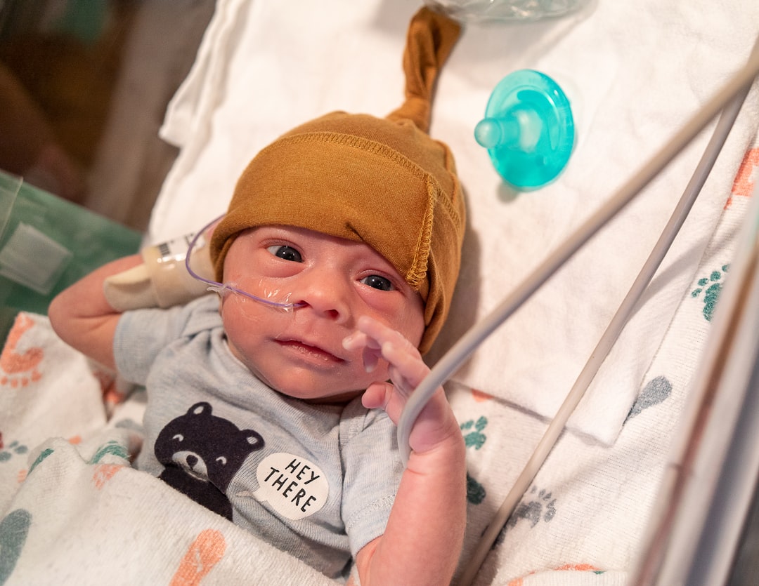 baby in orange knit cap and gray and white onesie