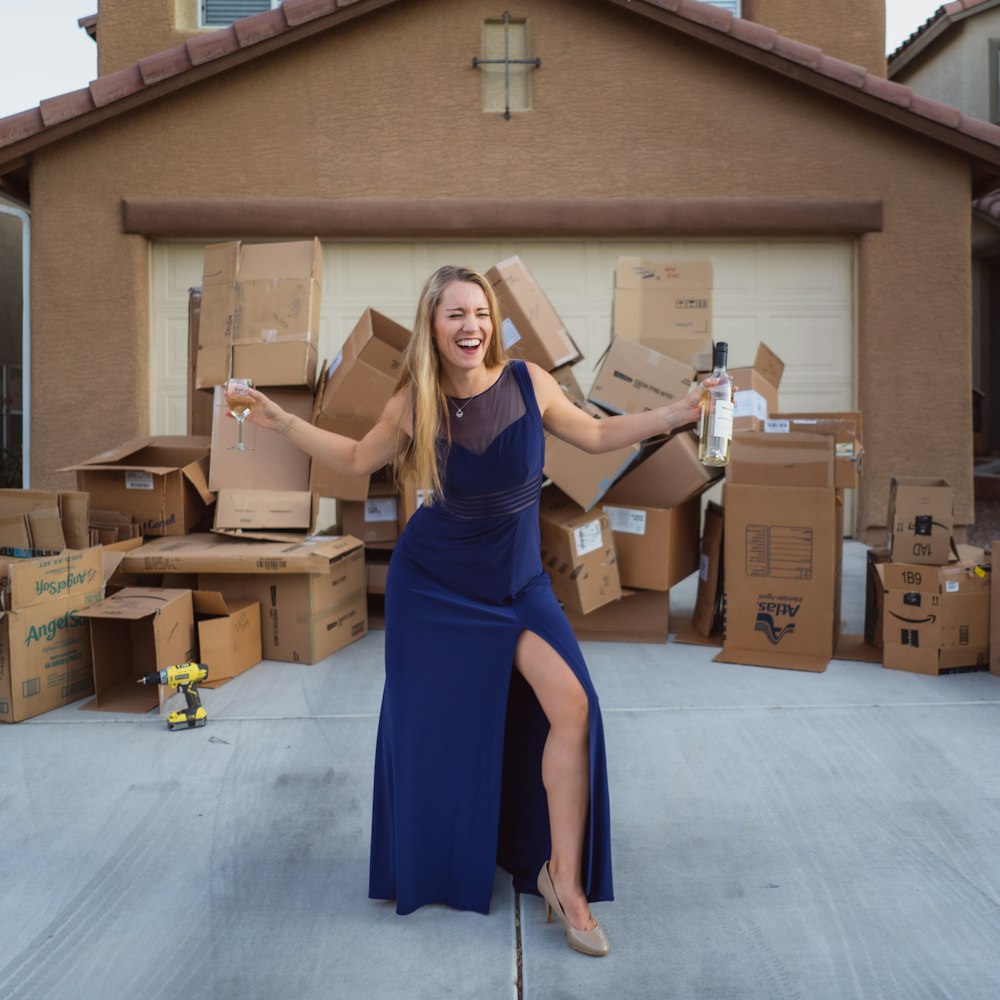 woman in blue dress holding brown cardboard box