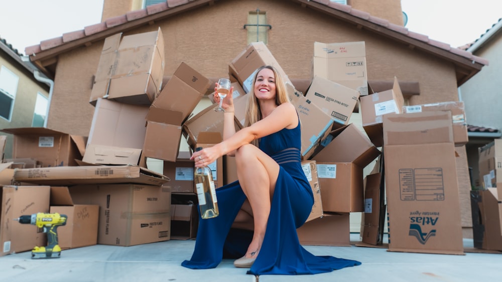 Femme en robe bleue sans manches tenant une boîte en carton marron