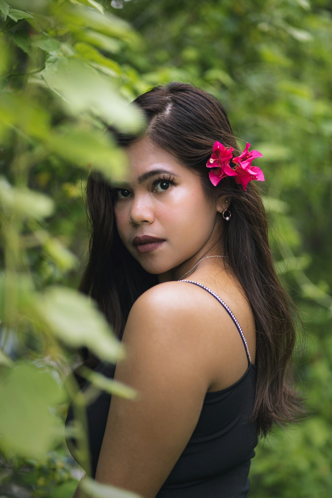 woman in black tank top with pink flower on her ear