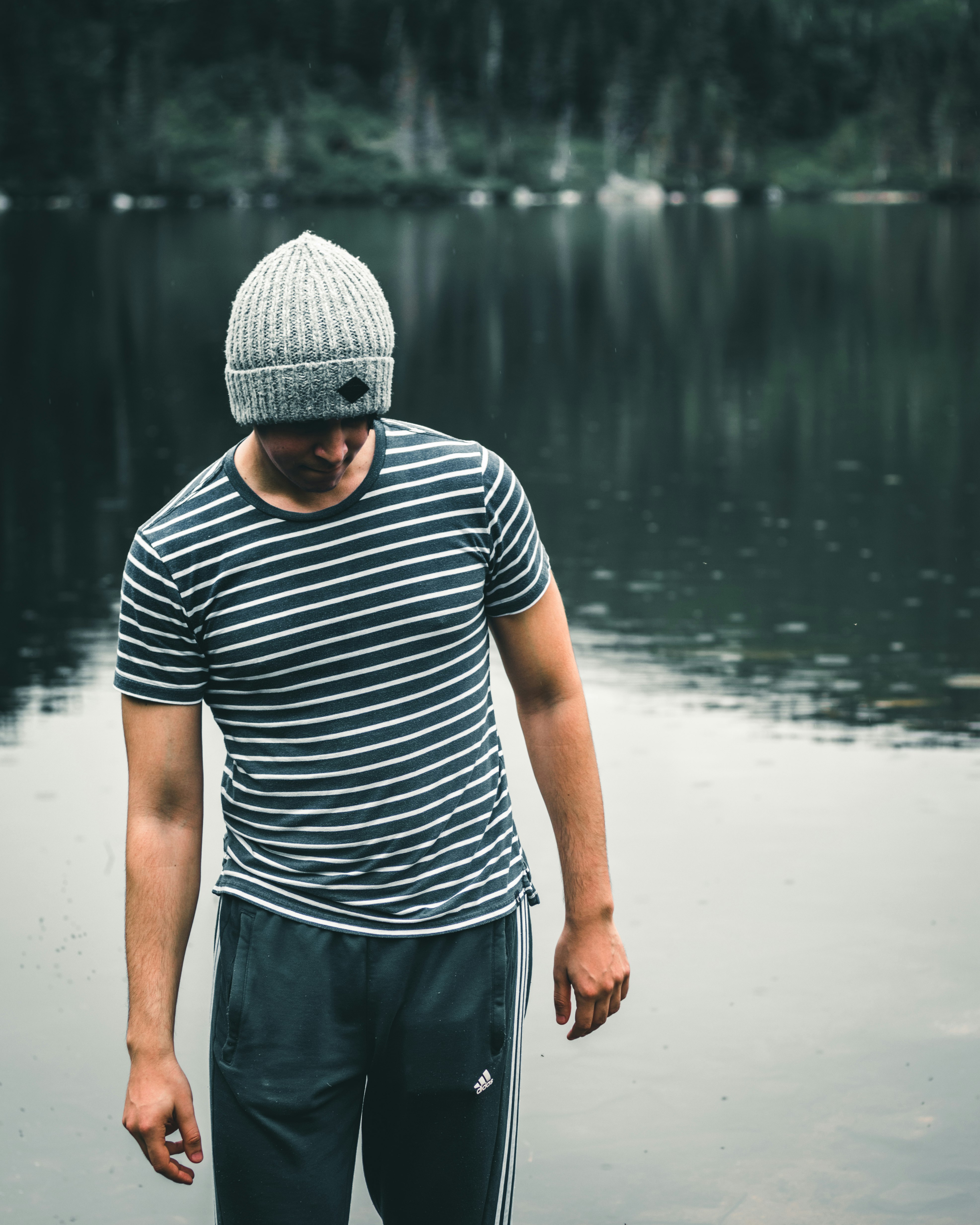 man in black and white striped shirt and gray shorts standing on water during daytime