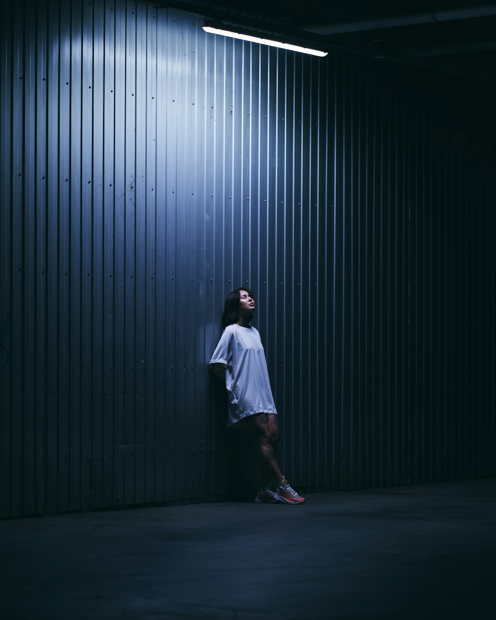 man in white t-shirt standing in front of gray wall