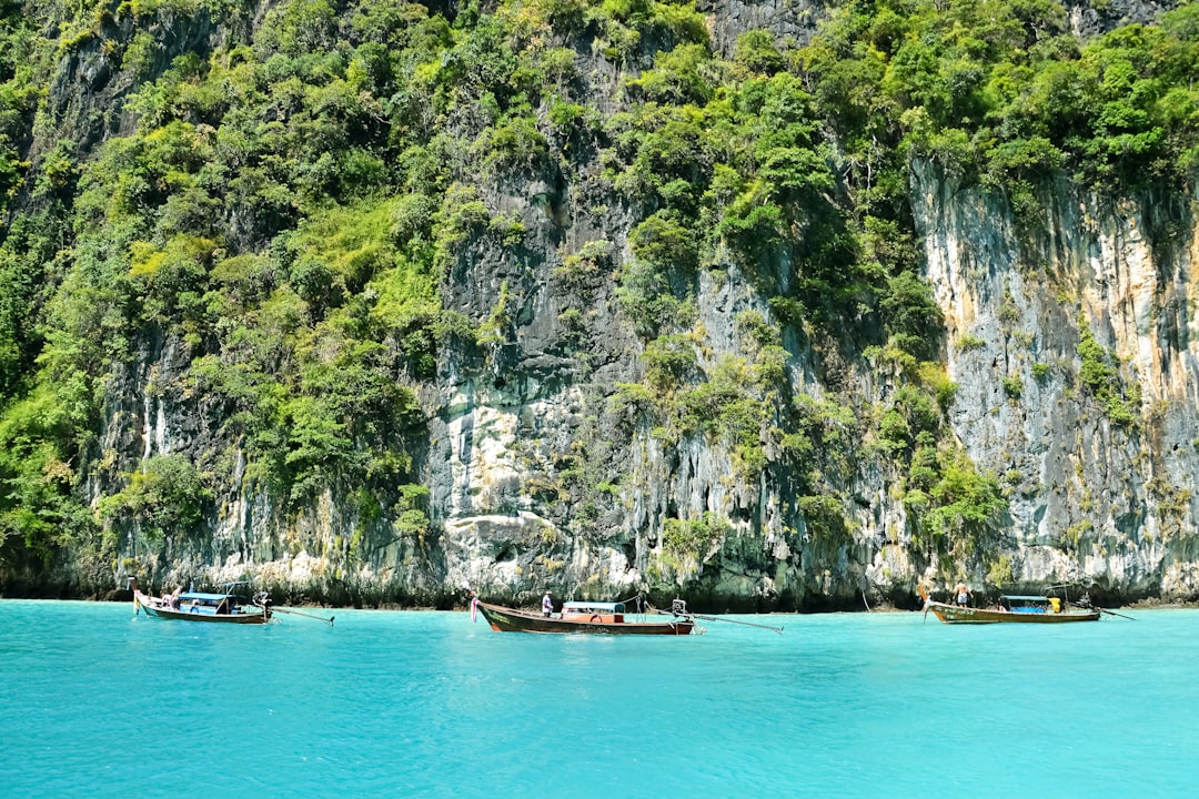 brown boat on blue sea near green and gray mountain during daytime