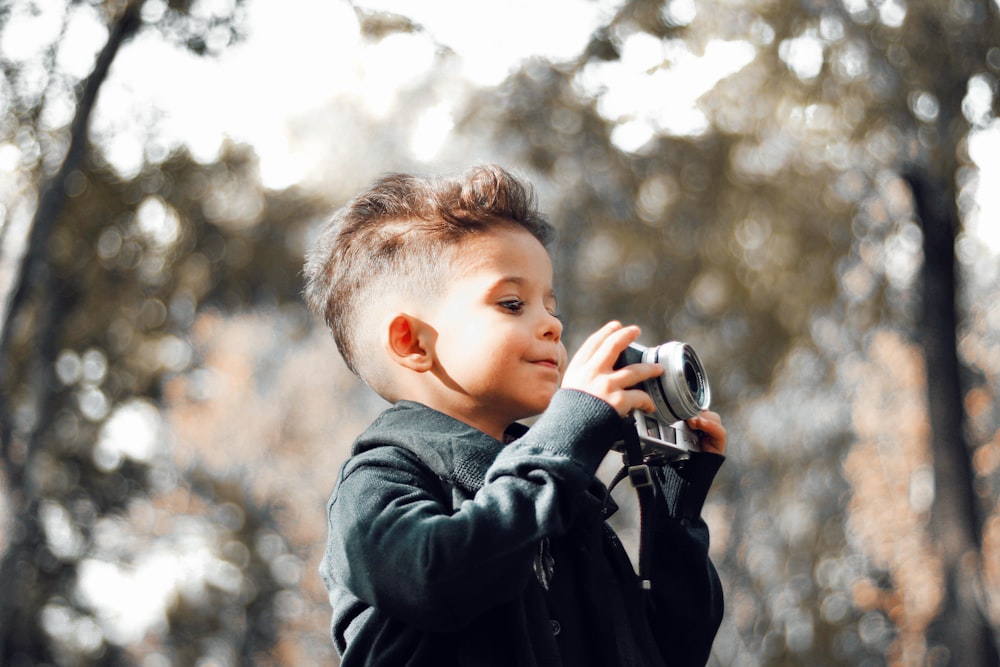 boy in black jacket holding camera