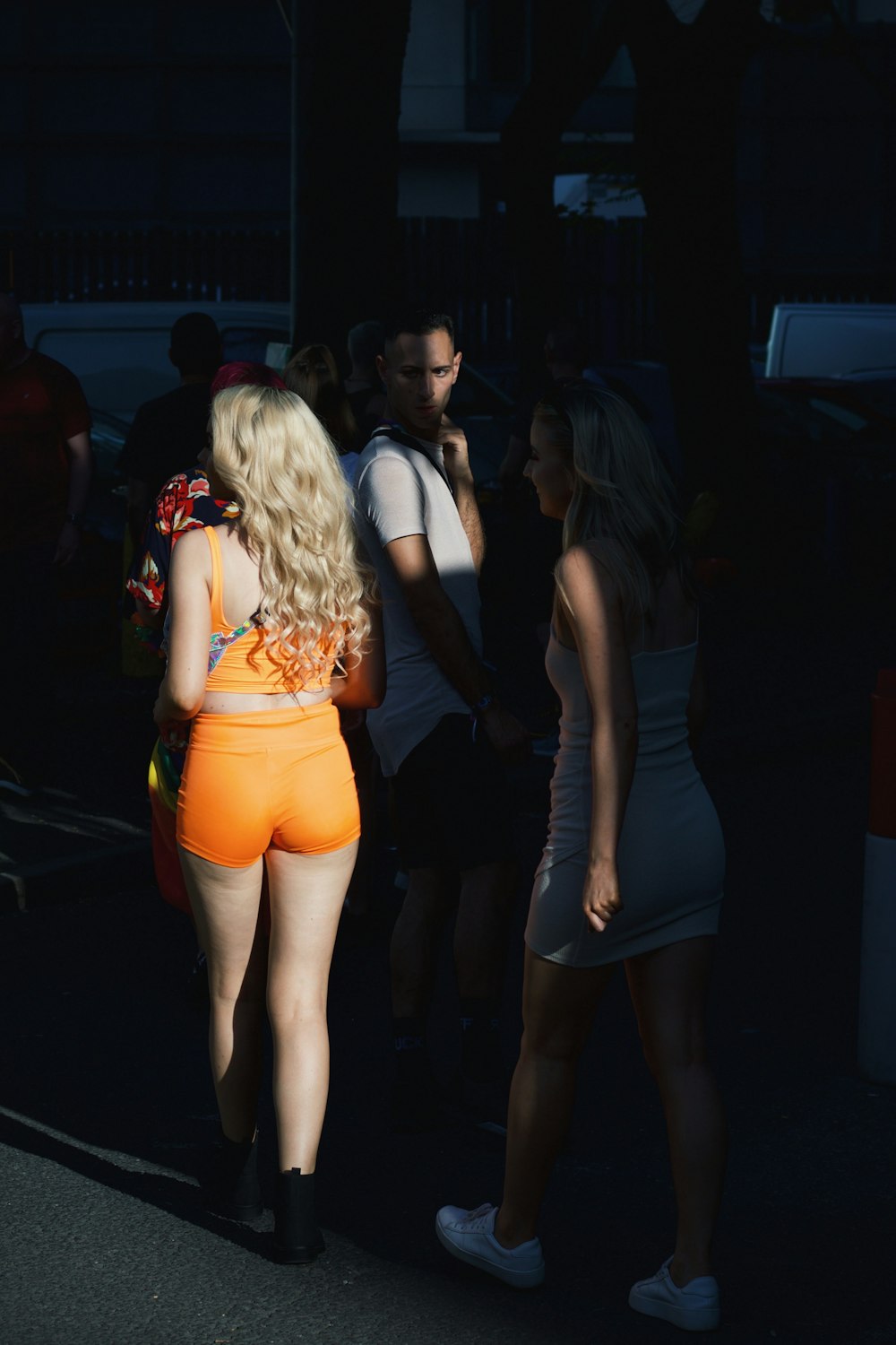 woman in blue tank top and blue denim shorts standing in front of woman in black